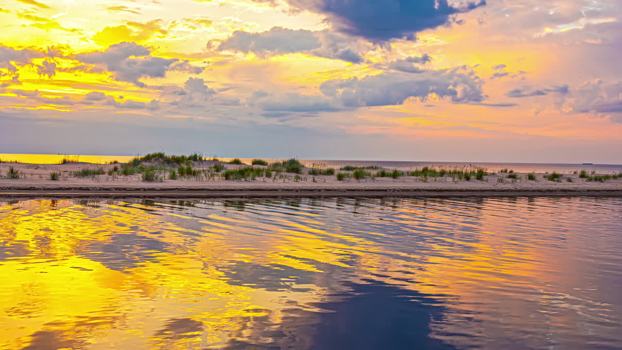 Fast motion landscape of golden sky with sun rays and clouds time lapse over lake inlet river channel early morning mirror reflection ripples in water nature travel tourism weather