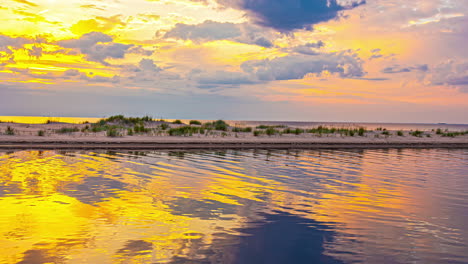 fast motion landscape of golden sky with sun rays and clouds time lapse over lake inlet river channel early morning mirror reflection ripples in water nature travel tourism weather