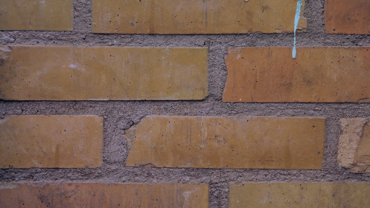 Tilt up shot to a closeup of a yellow and orange brick and mortar wall and a mounted white lightswitch that glows red