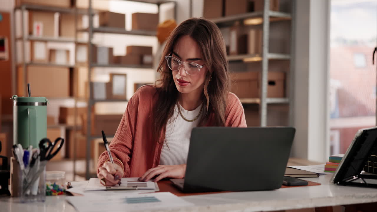Ung kvinne jobber på laptop og skriver på et lite kontor