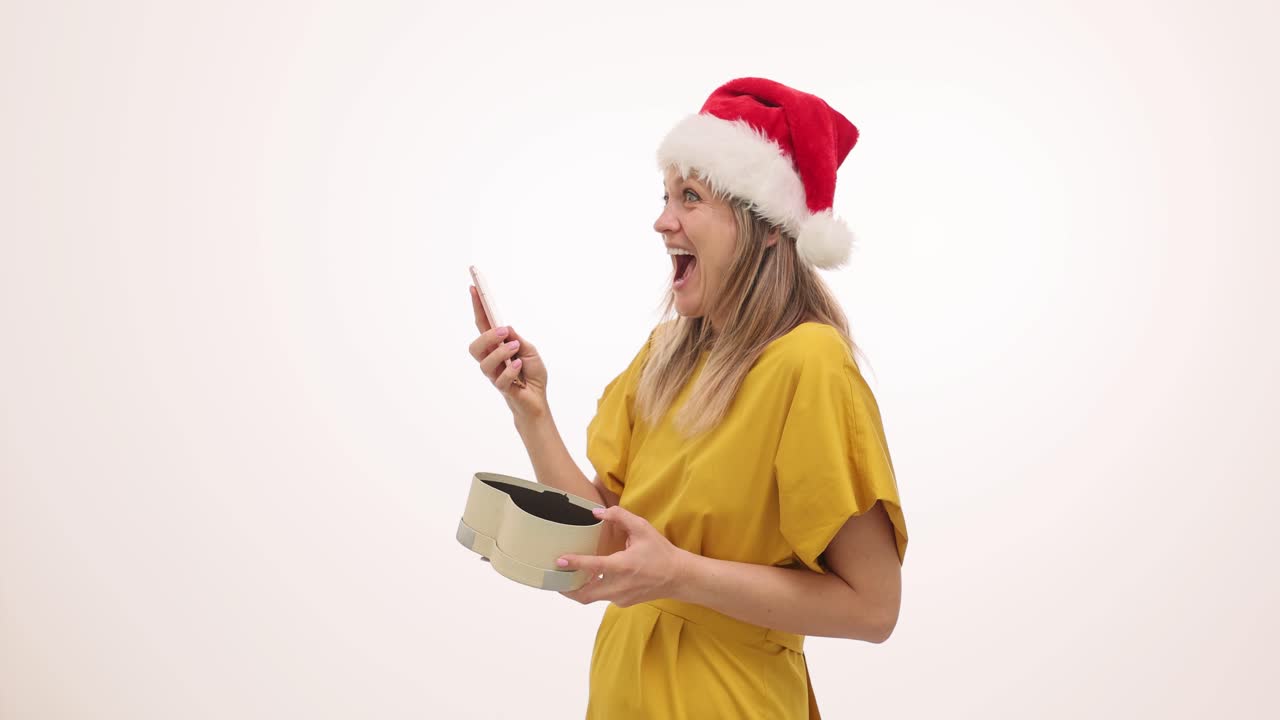 Woman in Santa hat with a gift and phone