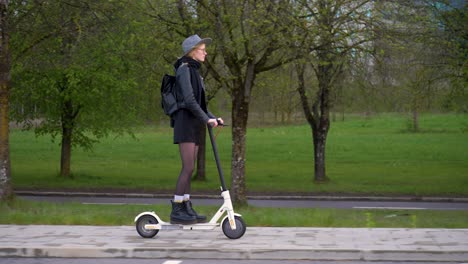 following side shot of stylish woman driving an electric scooter