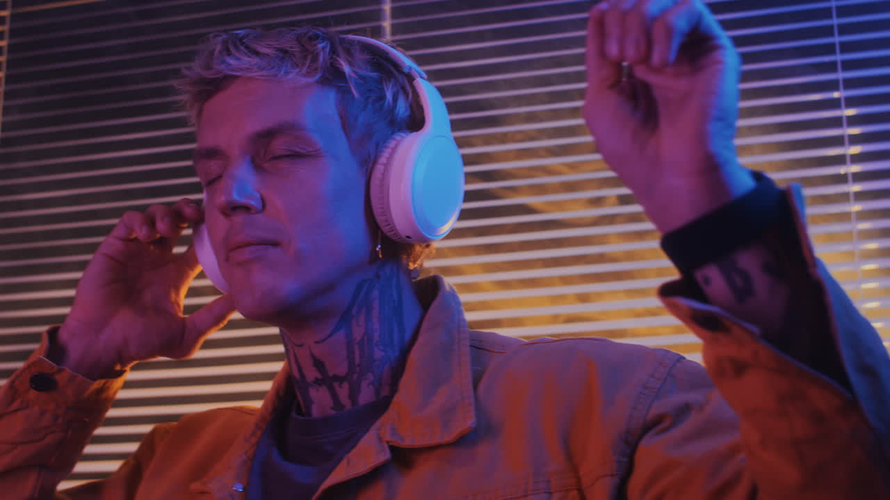 Young Man in Headphones Dancing Alone in Neon Light