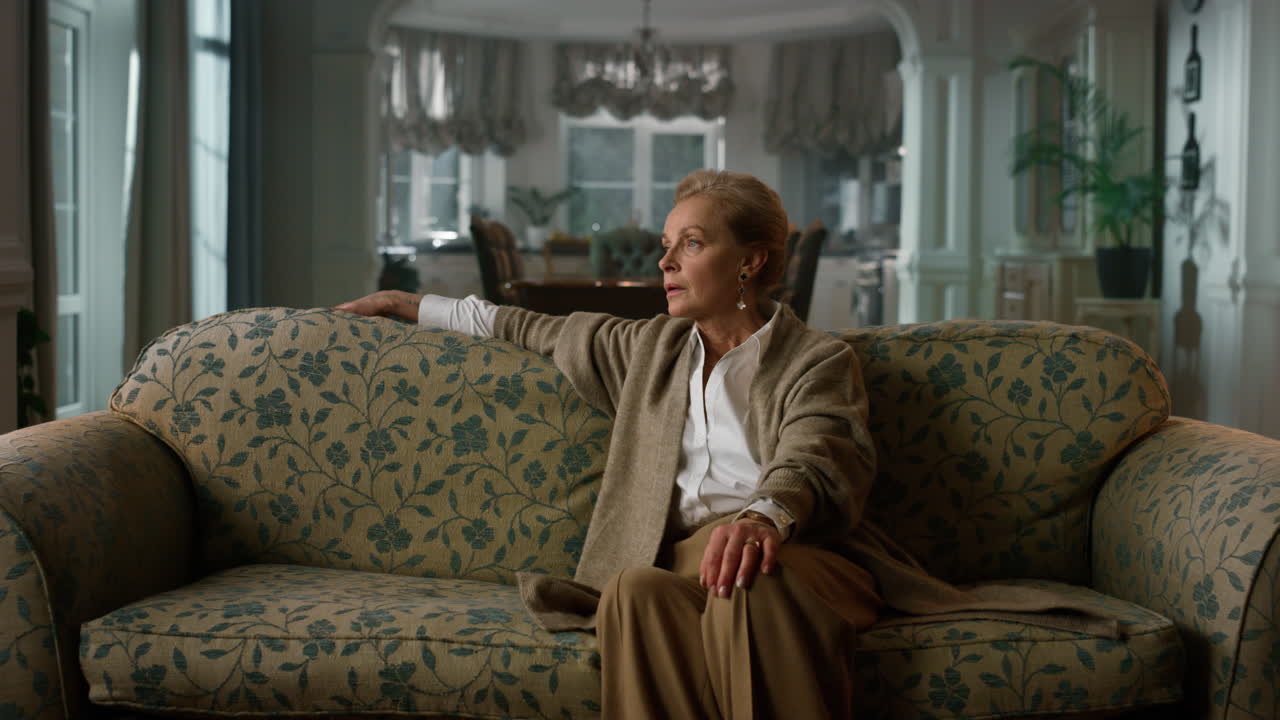 사치로운 집 의 소파 에 앉아 있는 사려 깊은 고위 여성