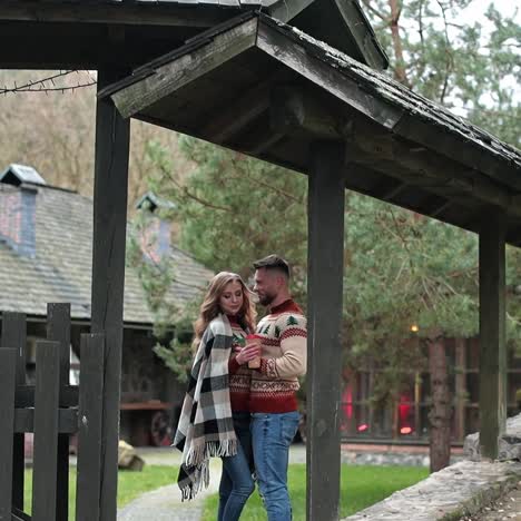 attractive couple in similar sweaters standing at the gates of a manor. autumn season in the countryside. cozy time-spending outside the big city