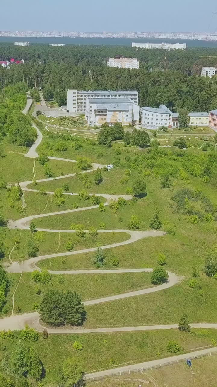 wonderful green hill with path of hairpin curves and round pavilion against distant town on nice autumn day aerial view