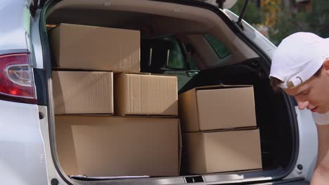 moving and delivery of manufactured goods. the loader puts craft boxes in the trunk of the car