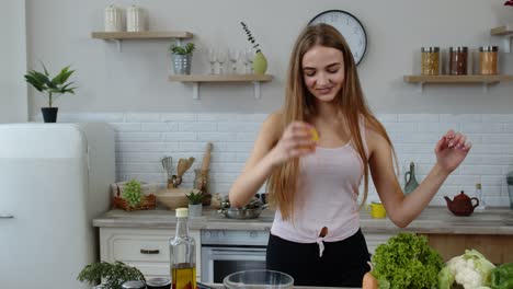 Girl-coming-to-table-with-juicy-lemon.-Young-woman-cutting-fresh-fruit-with-knife-and-smiling