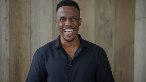 retrato de un joven afroamericano feliz riendo emocionado disfrutando de un estilo de vida exitoso con camisa negra en cámara lenta
