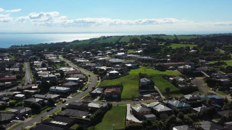 aerial coastal village rising over sunny bay water and green hills