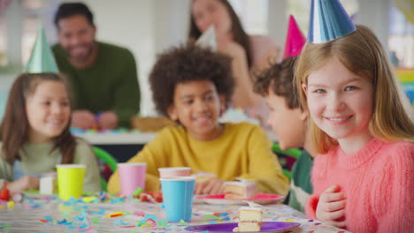 Portrait-Of-Girl-With-Birthday-Cake-At-Party-With-Parents-And-Friends-At-Home