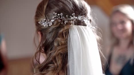 ajustando el velo de novia de la novia con cabello castaño rizado antes de la boda