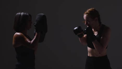 Foto-De-Estudio-De-Dos-Mujeres-Maduras-Vistiendo-Ropa-De-Gimnasio-Haciendo-Ejercicio-De-Boxeo-Y-Sparring-Juntas-Tomadas-De-Perfil