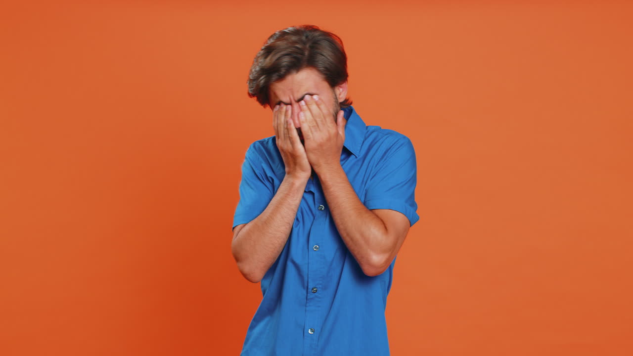 Afraid young man closing eyes with hand showing stop gesture, confused shy scared to watch, awful