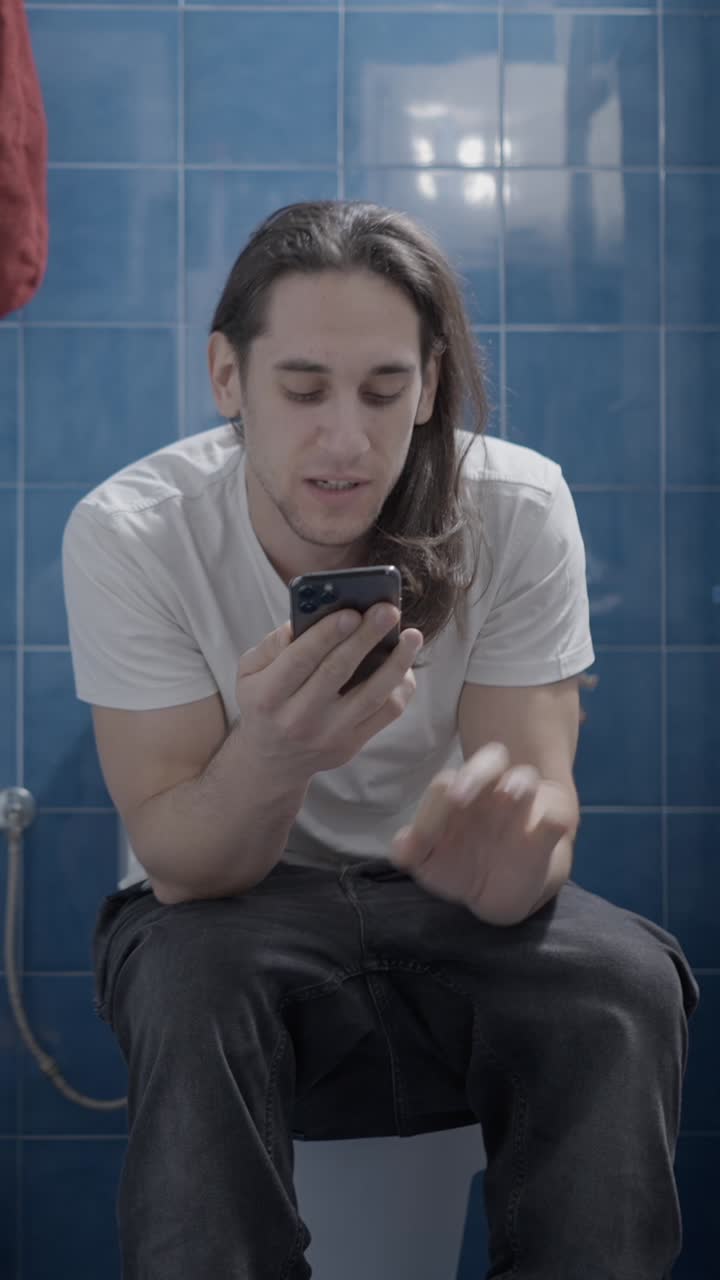 Man using a smartphone while sitting on a toilet