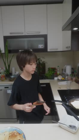 young boy cooking pancakes in the kitchen