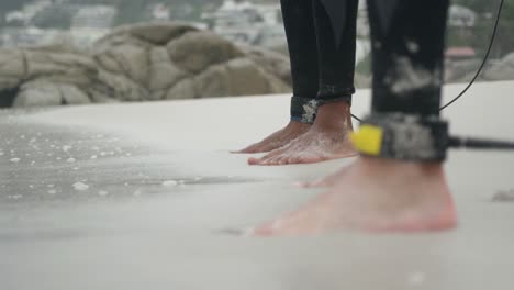 low section of two male surfers standing barefoot on the beach 4k