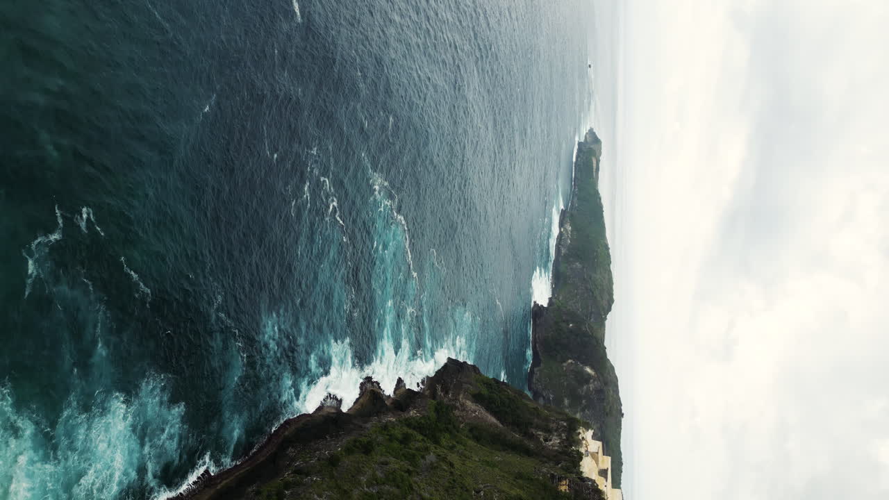 Aerial View of Ocean Waves Crashing Against Rocky Cliffs