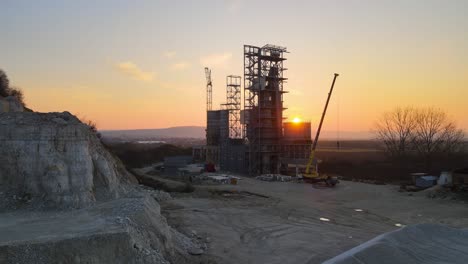 cement factory at open pit mining of construction sand stone materials. digging of gravel resources at quarry at sunset