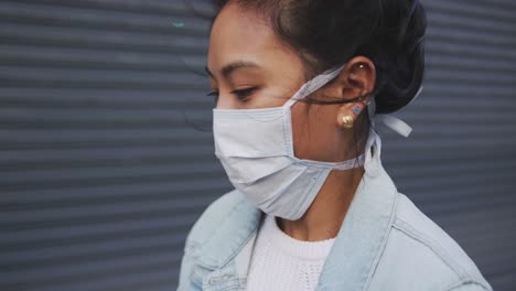 mixed race woman coughing on her medical coronavirus mask