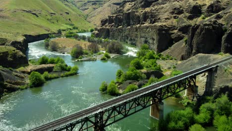 us, oregon, maupin, deschutes river, 2025-05-08 - drone view on the deschutes river of a train bridge at twin crossings which is two bridges and a tunnel. in north central oregon in spring