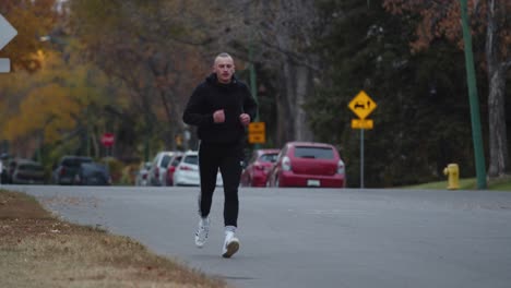 Man-running-down-a-road-through-a-neighborhood-with-green-trees-and-street-signs