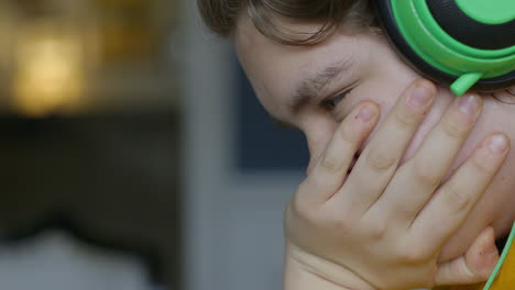 Teen-boy-wearing-headphones-and-looking-downward-concentrates,-close-up-profile