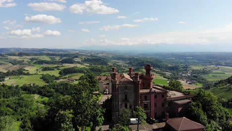 Drone-pan-left-above-Novello-castle,-revealing-the-amazing-panorama-of-Langhe-during-a-sunny-summer-day