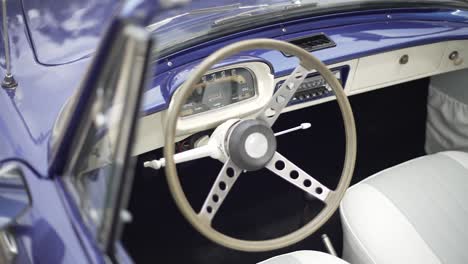 interior de un coche azul vintage con volante blanco
