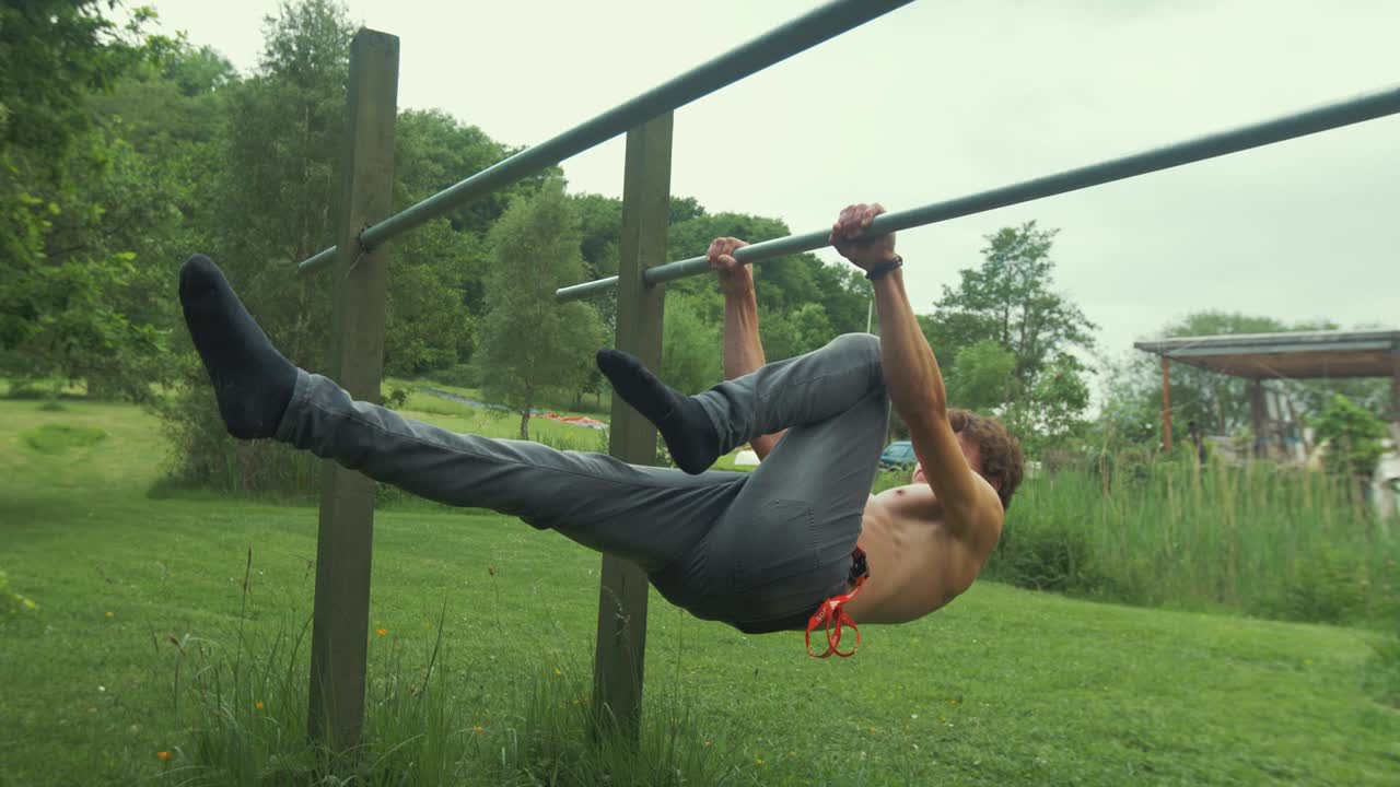 jóvenes en topless en forma masculina realizando palanca frontal de pierna al aire libre en barras paralelas gimnasio en casa