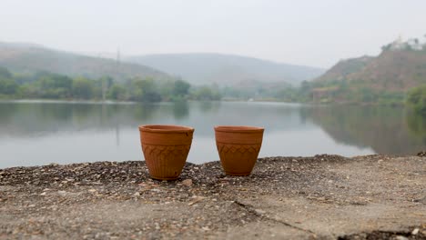 hot tea served in traditional handleless pottery clay cup with blurred mountain lake landscape