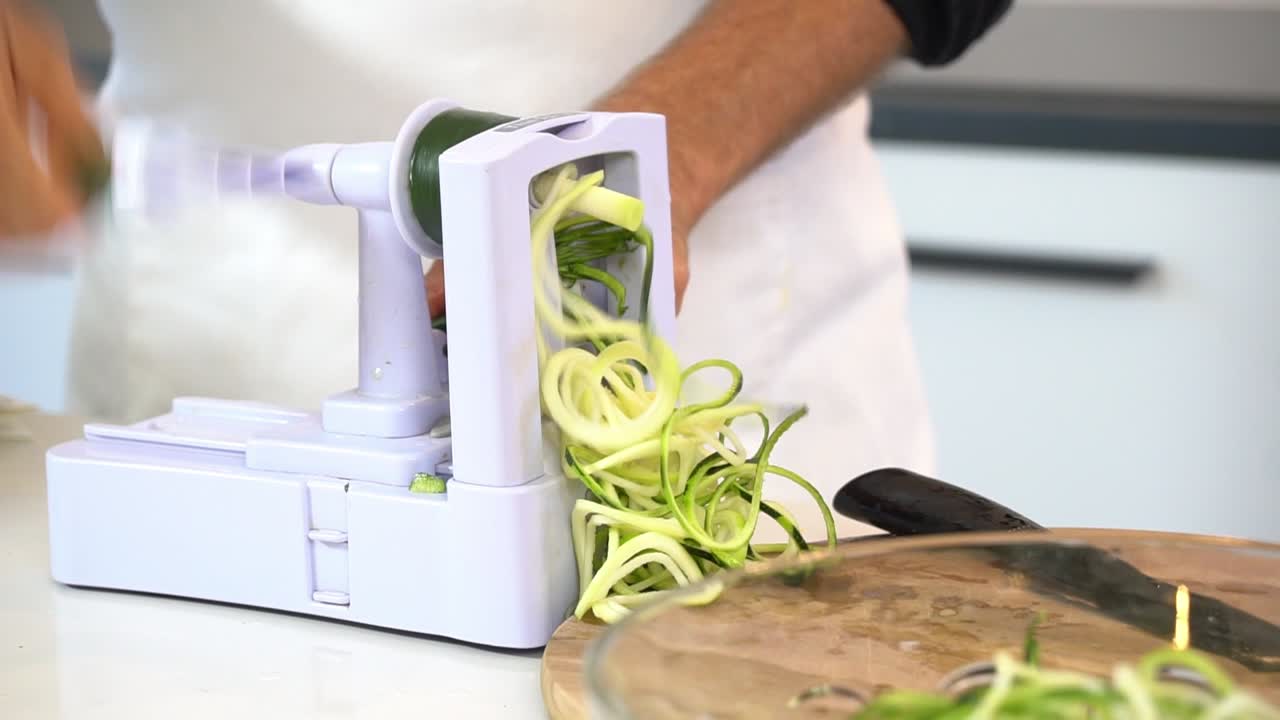hombre en espiral calabacín para hacer calabacín fideos zoodles añadiendo a la taza saludable vegano vegetariano estilo de vida dieta de desintoxicación