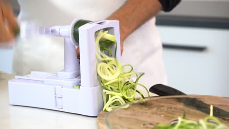 man spiralizing zucchini to make zucchini noodles zoodles adding to bowl healthy vegan vegetarian lifestyle diet detox