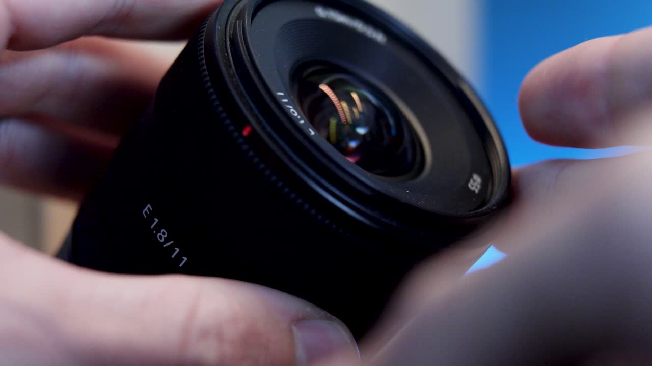 Close-up of a camera lens held by a person, highlighting its intricate design, precision glass elements, and connection to photography, creativity, and professional imaging.