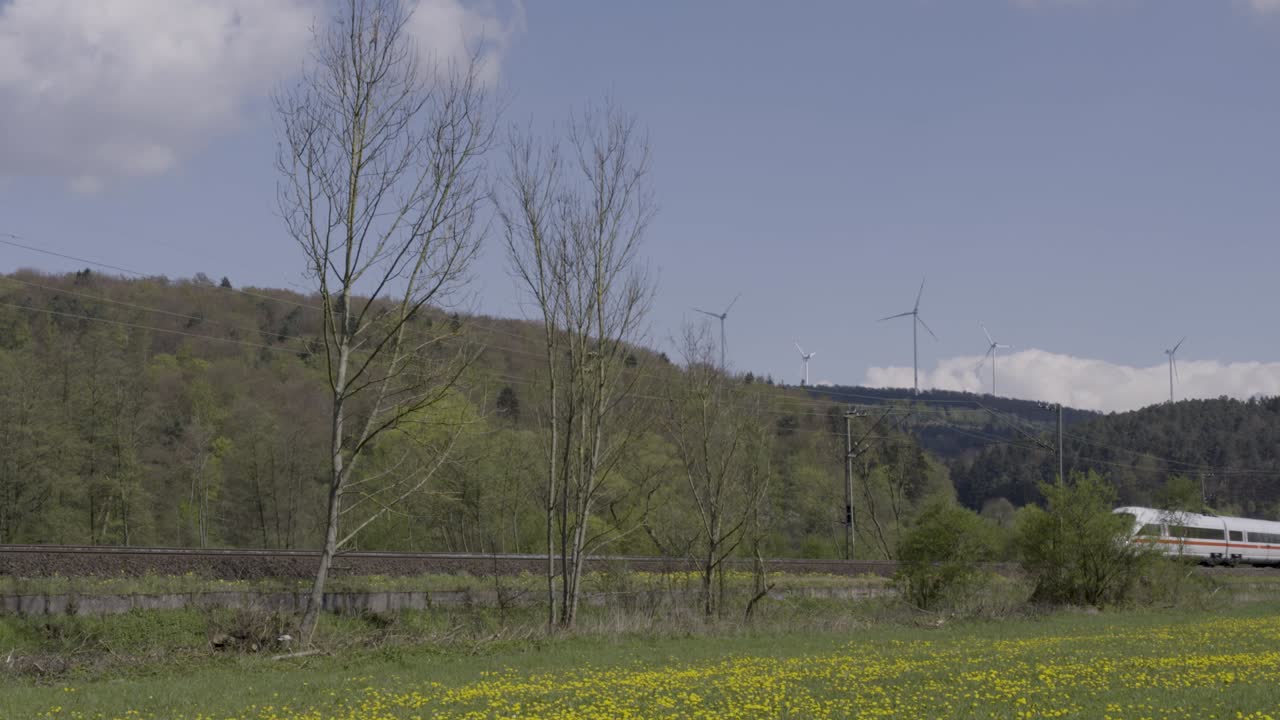 풍력 터빈을 배경으로 활기찬 시골 풍경을 통해 고속 열차가 가속화, 은 날