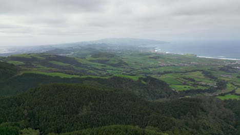 Aerial-reveal-of-pastures,-forest-patches-and-shoreline-in-São-Miguel-Azores