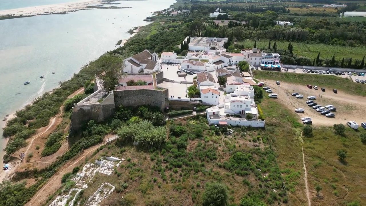 Filmato aereo con drone di Cacela Velha, Portogallo: storico villaggio bianco, laguna costiera e litorale atlantico sotto una luce chiara. Ideale per progetti di viaggio e turismo.