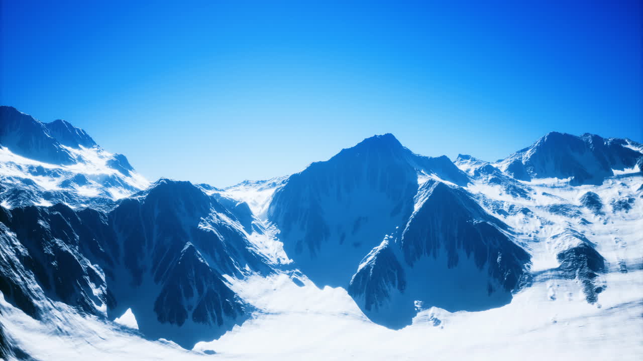 Snowy mountain peaks under clear blue sky in winter landscape view