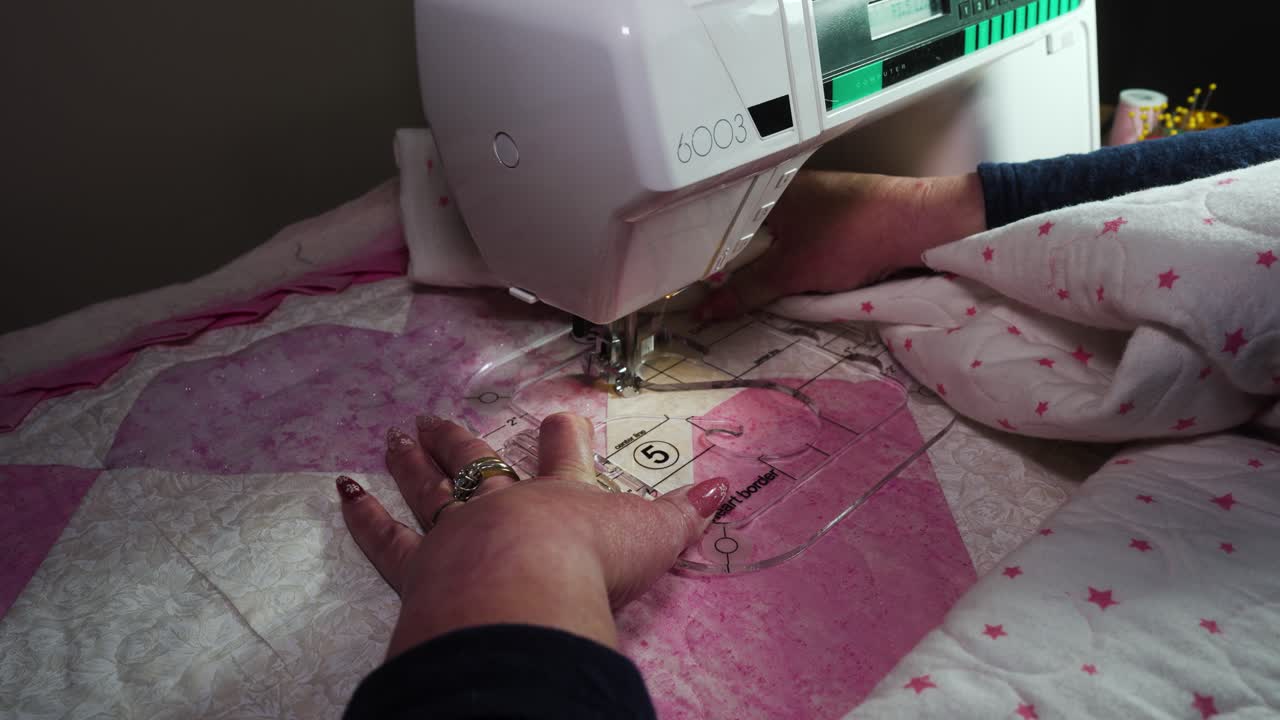 Using a plastic template fitted on a sewing machine to stitch a pattern into a handmade quilt - isolated
