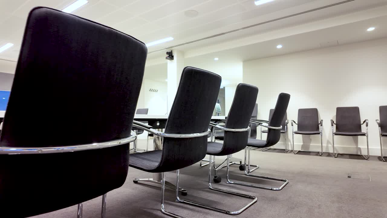Interior de sala de juntas con sillas negras y mesa de conferencias para reuniones de negocios y presentaciones. Espacio de oficina moderno con diseño minimalista