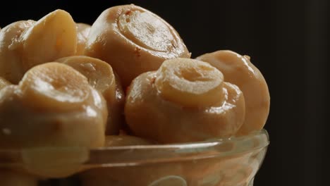 fermented champignons, jar with marinated mushrooms on wooden table, traditional salted marinated asian food.