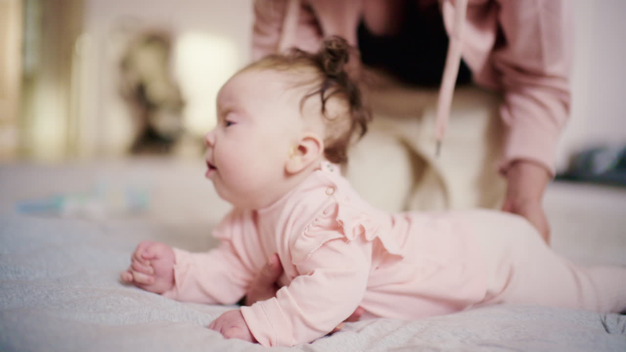 Baby øver på magetrening på en myk overflate mens en forelder støtter bakfra