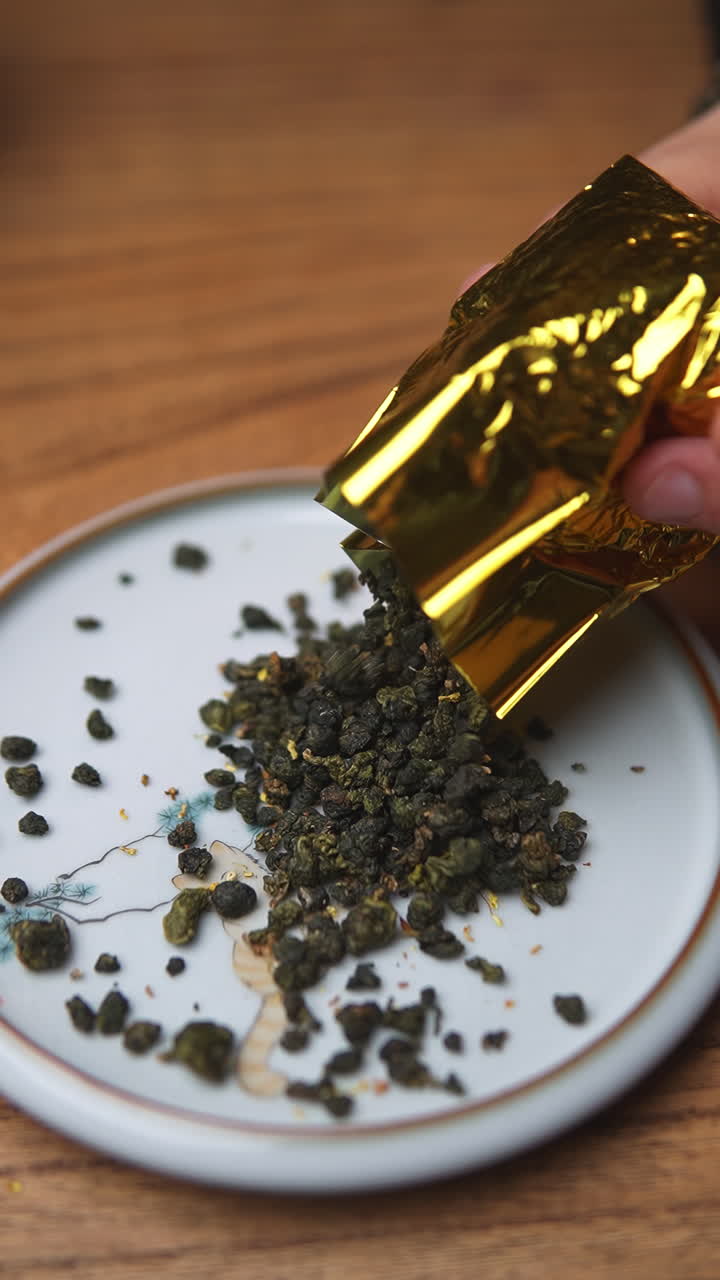 Foglie di tè Oolong che si versano da una bustina in lamina d'oro su un piatto