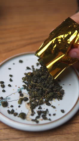 oolong tea leaves pouring from gold foil packet onto plate