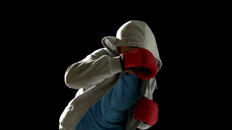Uomo in forma che sferra pugni con guantoni da boxe su sfondo nero