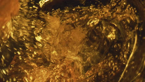 craft beer swirling splashing closeup. golden lager stream creating bubbles