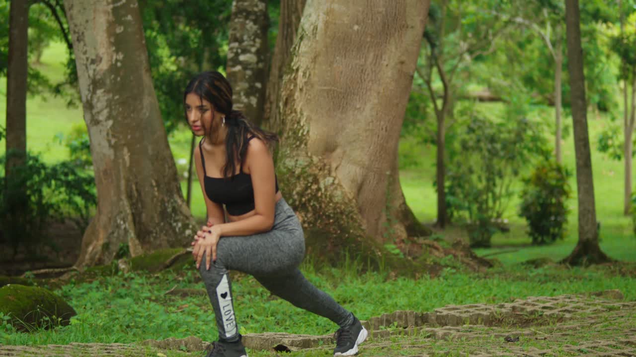 usando equipo deportivo, una joven hace ejercicios en medio del exuberante entorno del parque tropical