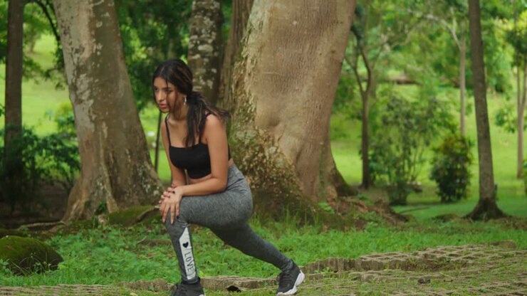 Wearing sports gear, a young girl exercises amidst the lush setting of the tropical park
