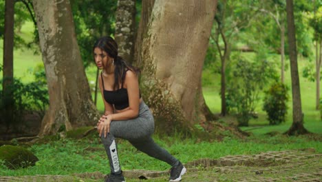 Wearing-sports-gear,-a-young-girl-exercises-amidst-the-lush-setting-of-the-tropical-park