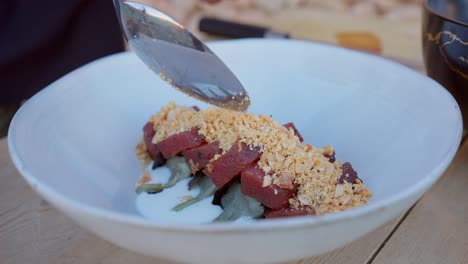 chef prepara comida mediterránea con atún crudo y almendras trituradas